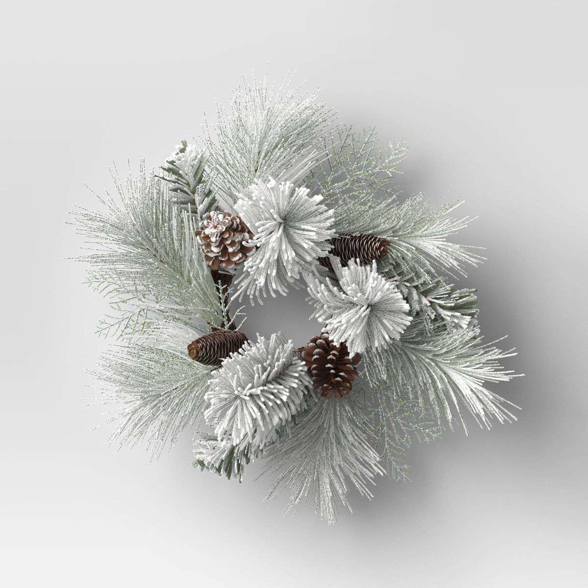 Mini corona de hojas de pino blanco y piñas de Target mostrada sobre un fondo blanco en blanco