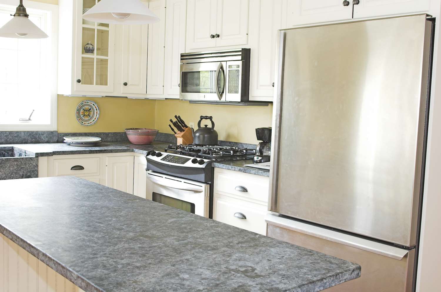 Cozinha campestre ensolarada com balcão de pedra e aço inoxidável