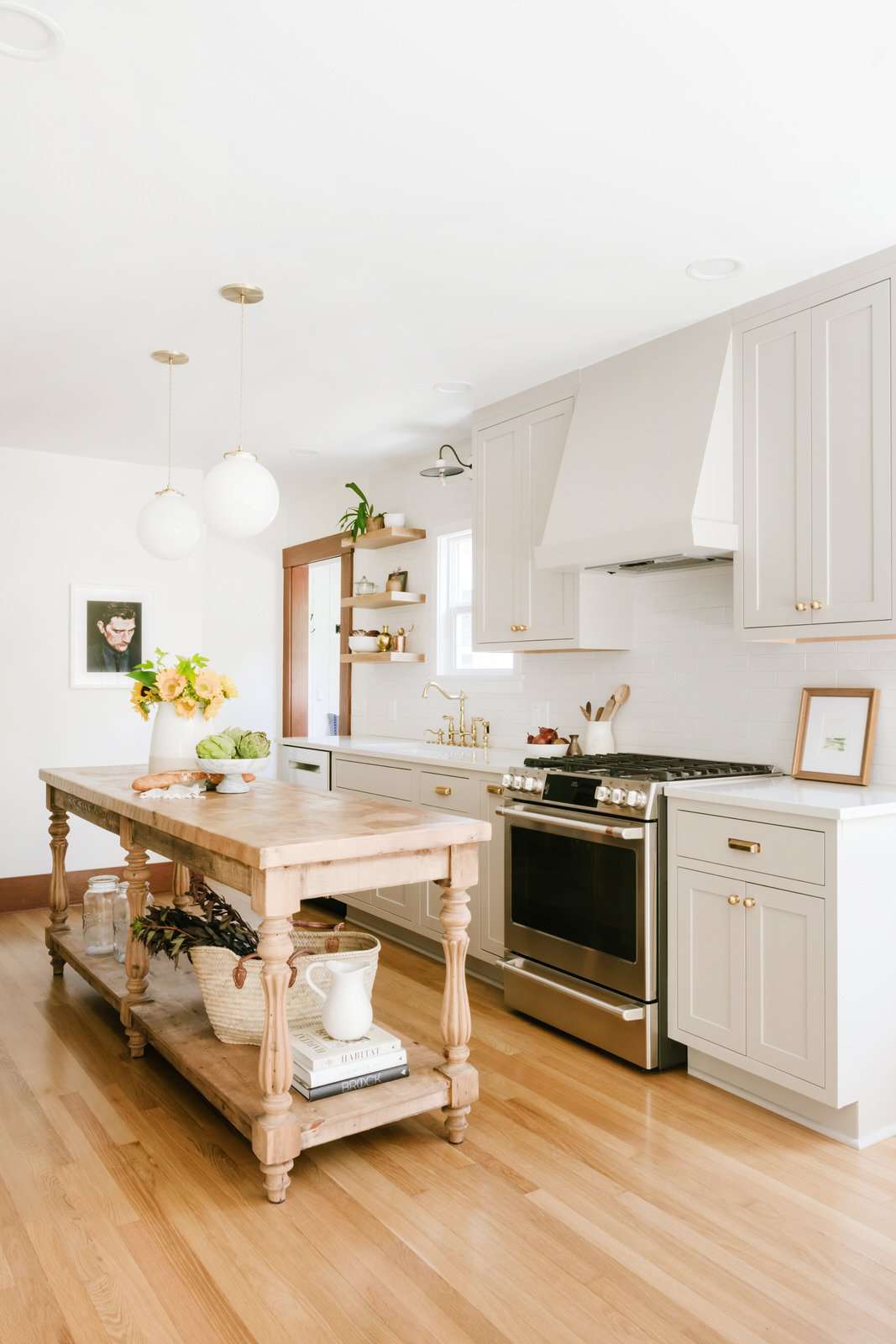 Eine komplett weiße Küche mit einem rustikalen Küchentisch, der zu einer Insel umfunktioniert wurde