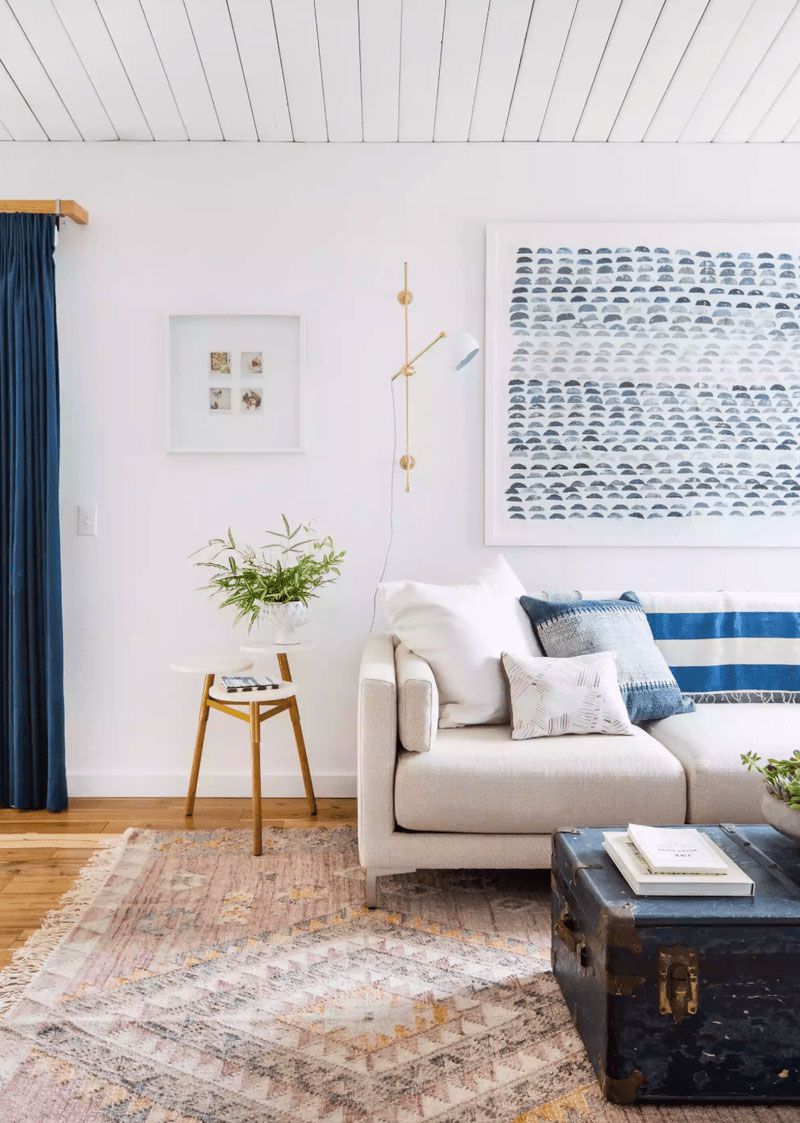 Sala de estar com teto de painéis de madeira pintados de branco e detalhes em azul por toda parte