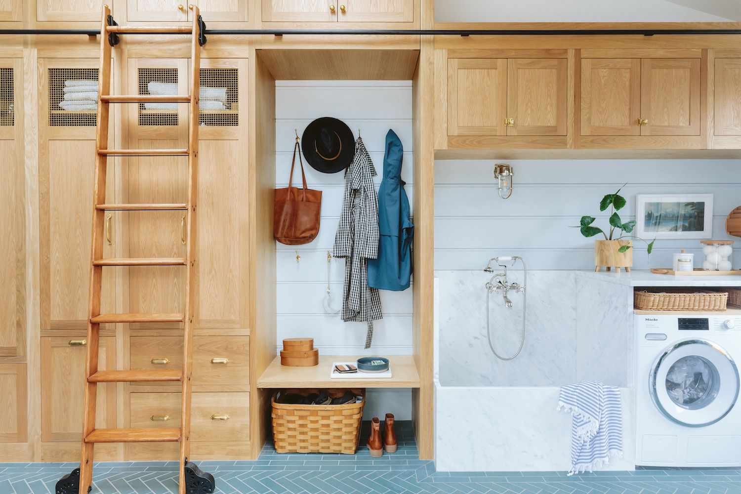 Lavadero rústico con armarios de madera clara, suelo de espiga de baldosas azules y bañera de mármol blanco para perros