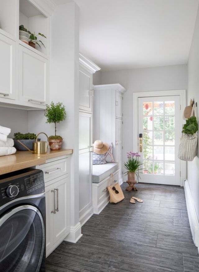 Rustikale Waschküche mit weißen Schränken und grauem Kachelboden