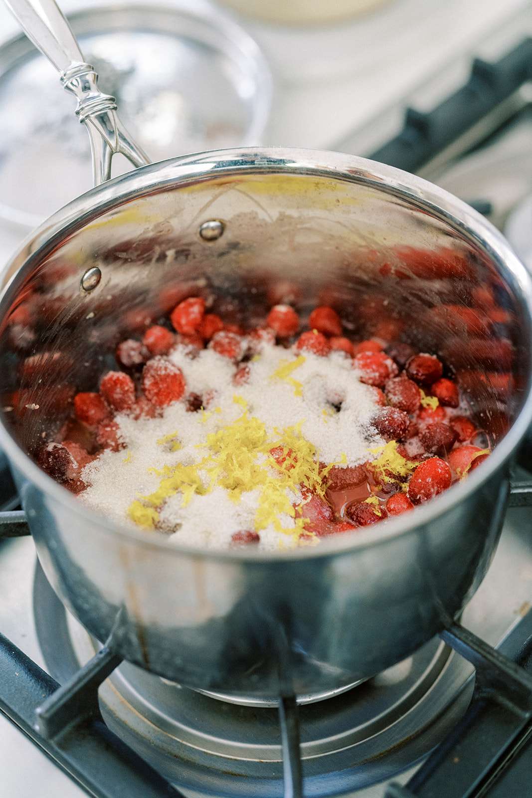 Uma panela com cranberries, açúcar e raspas de limão fervendo no fogão