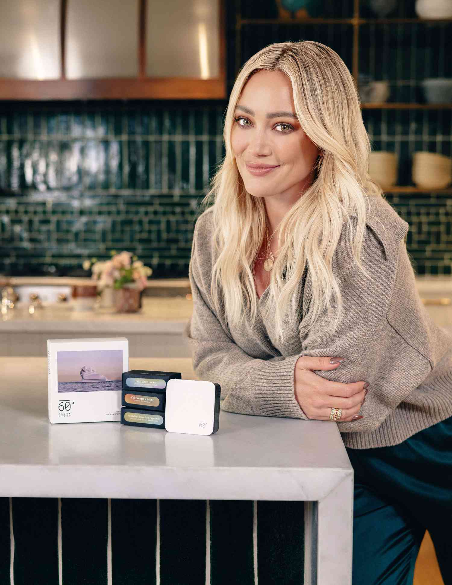 Hilary Duff posando junto al kit de inicio de aceites esenciales con tres aceites esenciales y el difusor de fragancias sin caja