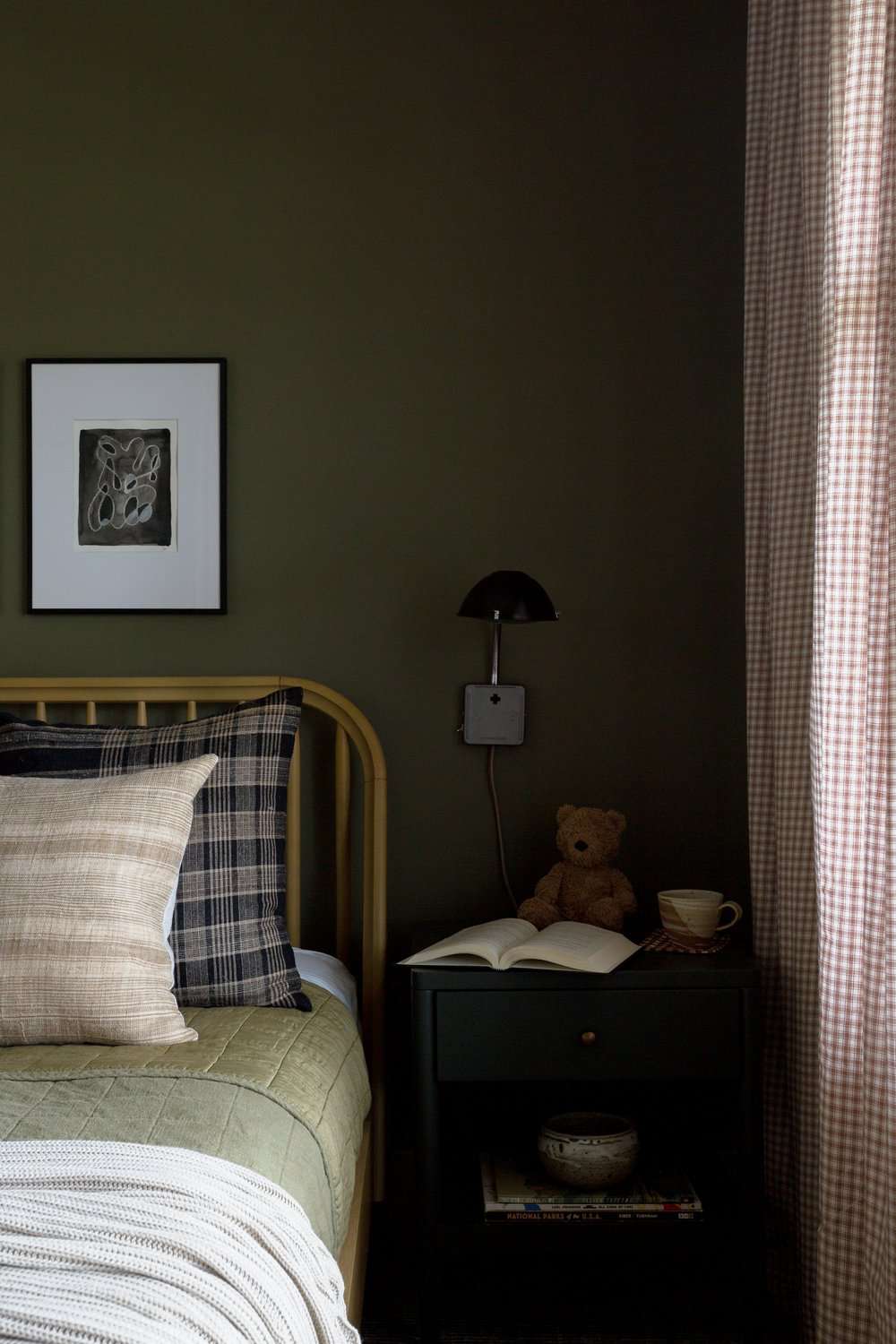 Parede verde-escura atrás de uma cama em um quarto de criança
