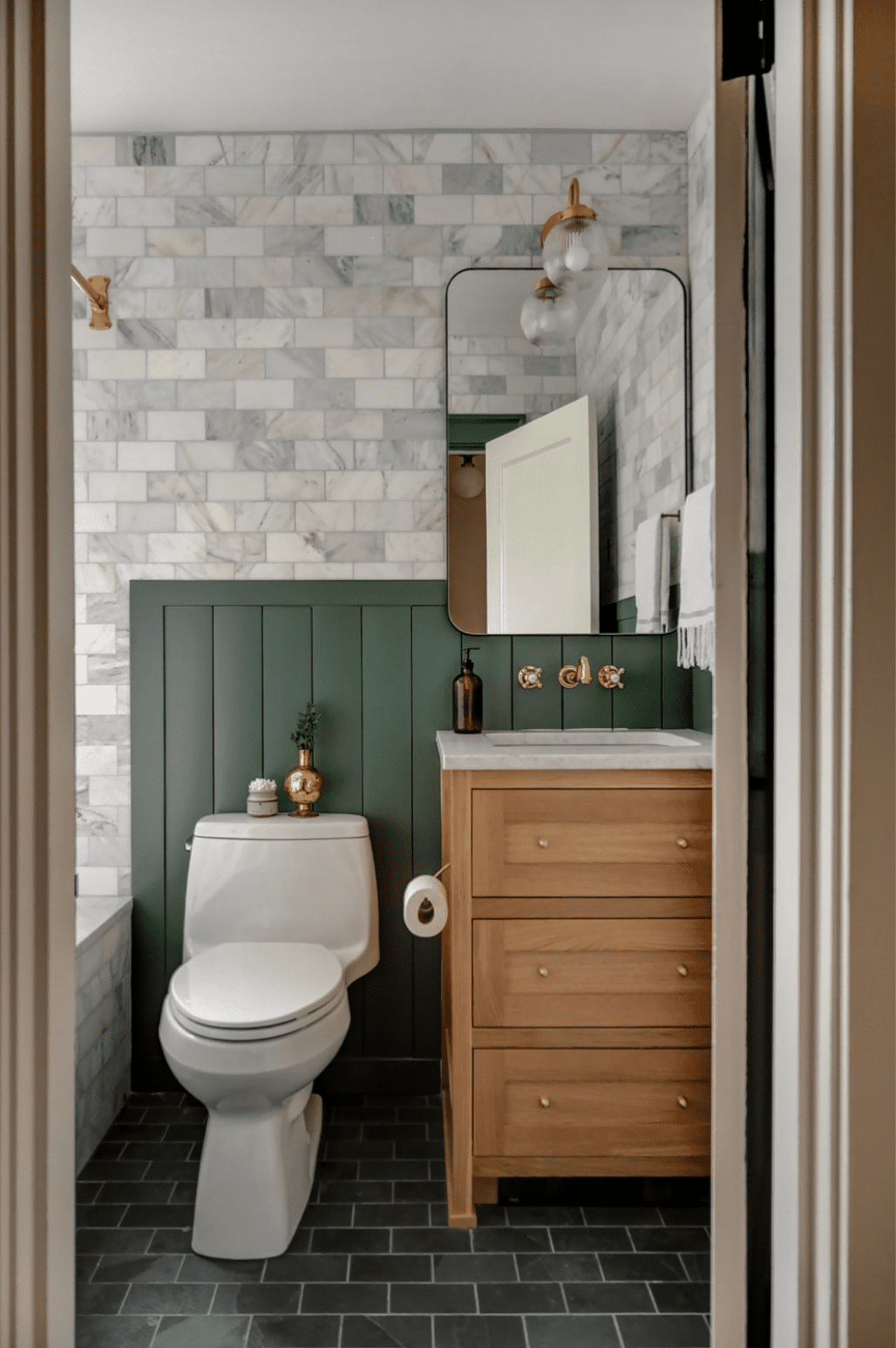 Banheiro com azulejos de mármore e parede com detalhes em verde