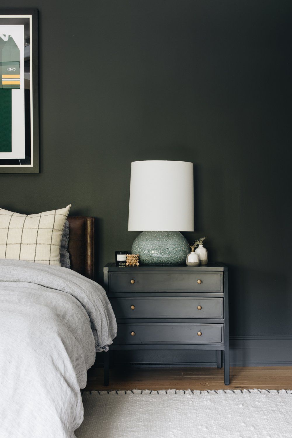 Dunkelgrüne Wand in einem Schlafzimmer hinter einem Lederkopfteil