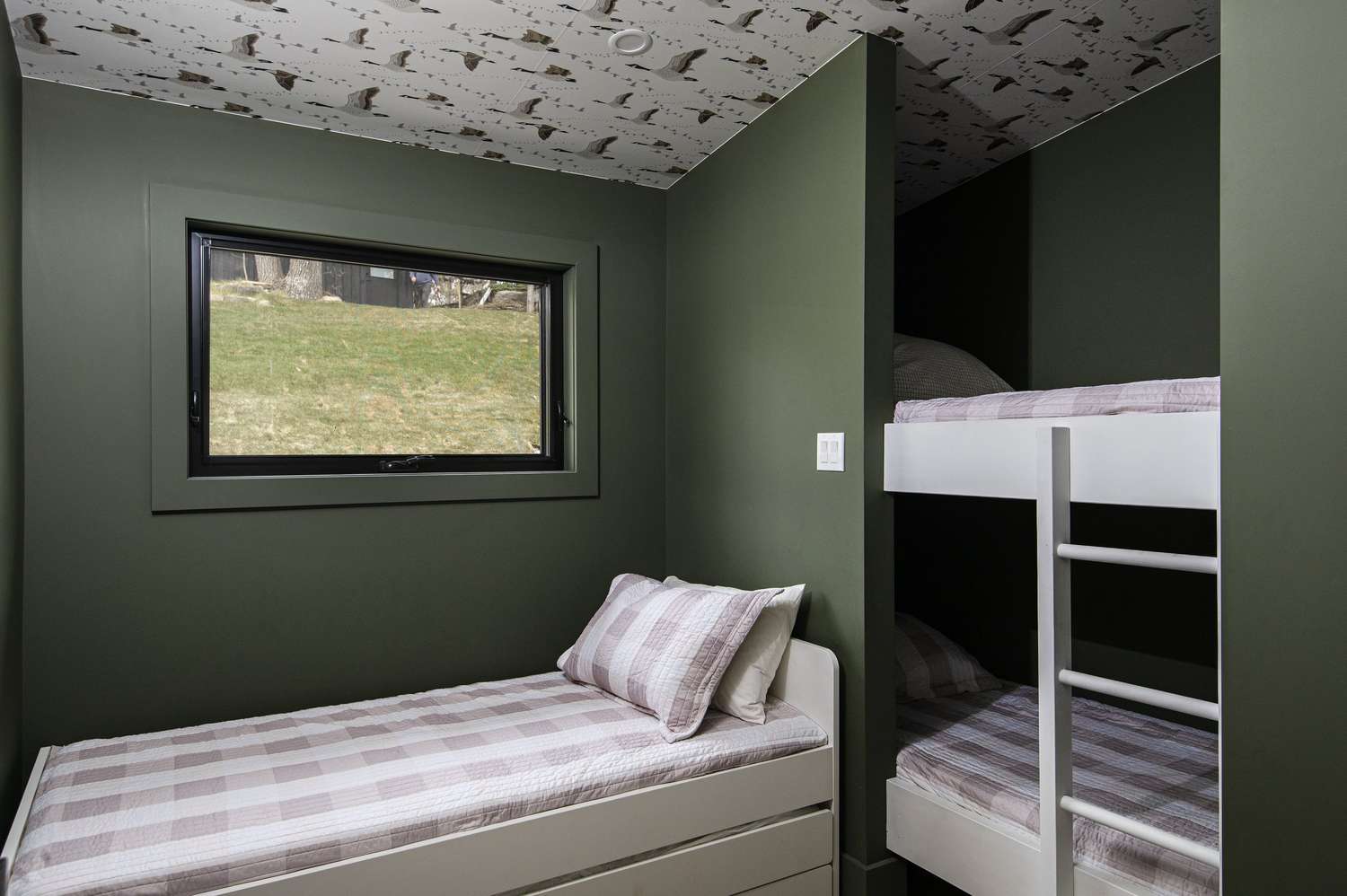 Green walls and wallpapered ceiling in a bedroom with bunk beds