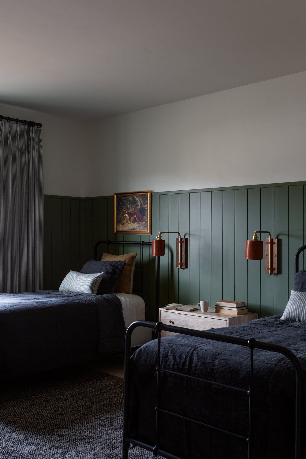 Painéis de parede verde-escuro em um quarto com duas camas de solteiro