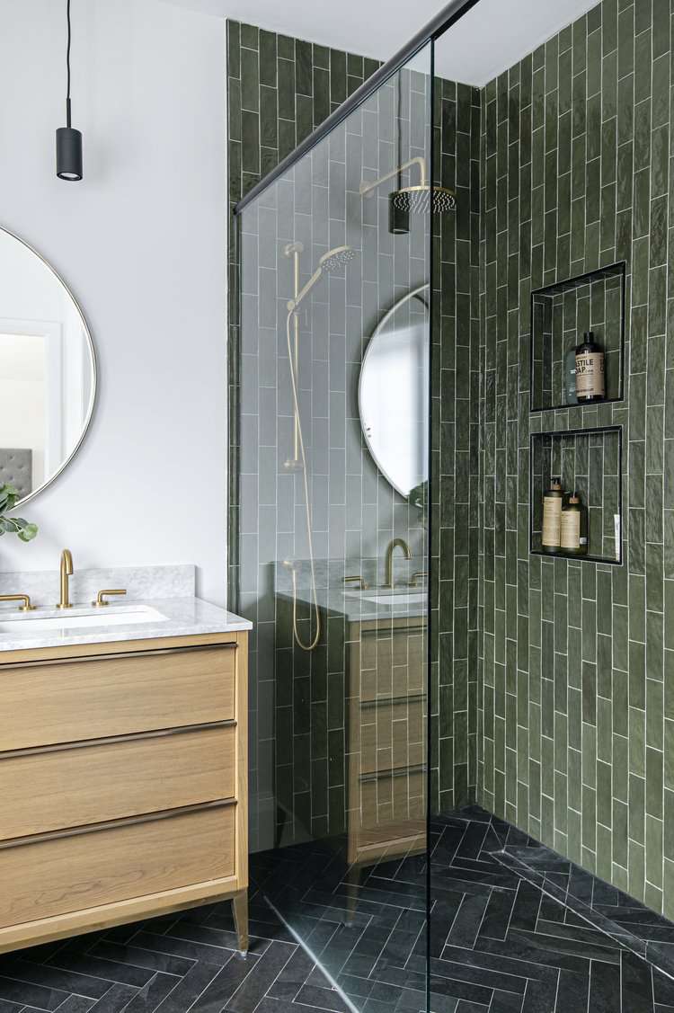 Pared de acento de azulejos verdes en una ducha con puerta de cristal