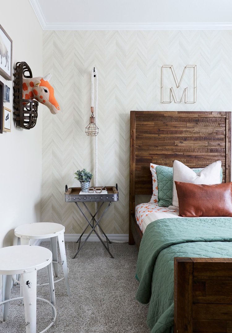 Dormitorio infantil con ropa de cama de edredón verde azulado y arte de cabeza de pared de jirafa de felpa naranja