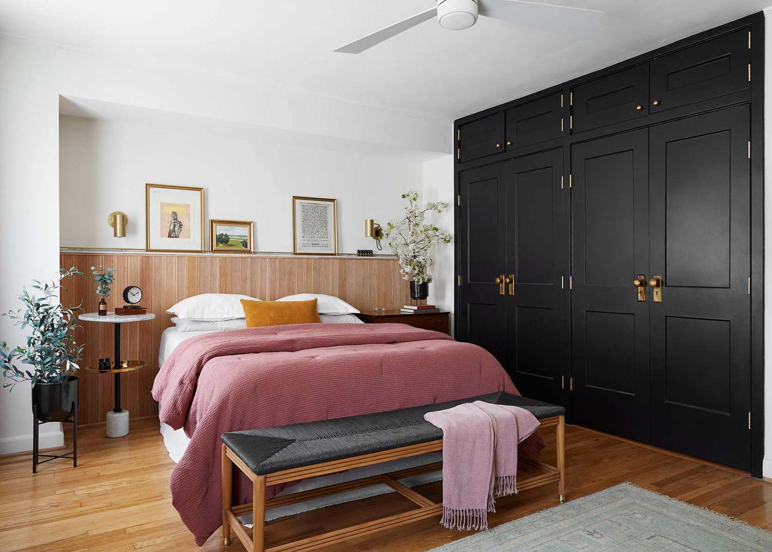 A peach colored bed sits next to a black accent wall