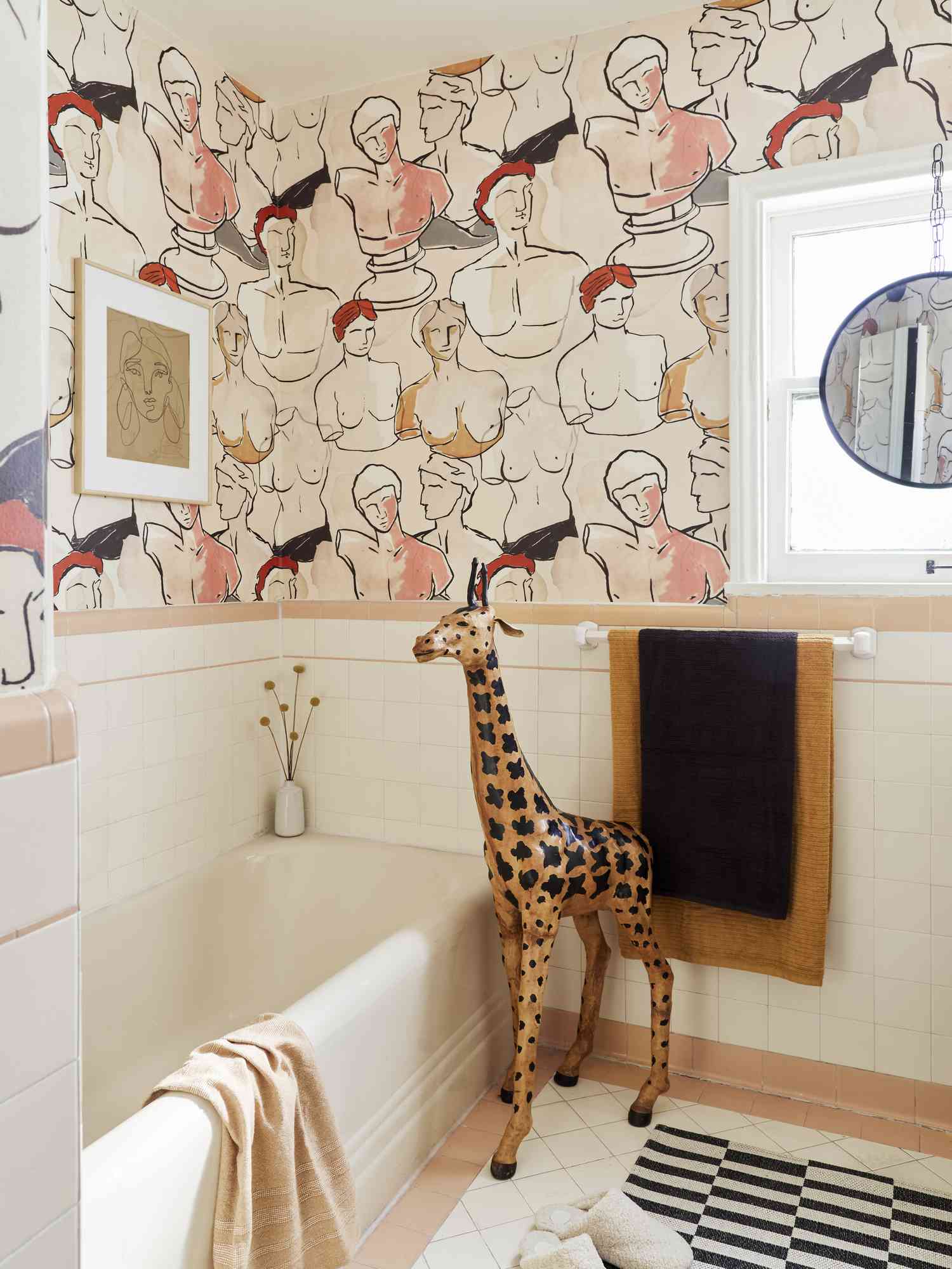 Um banheiro é coberto por um mural composto por bustos clássicos em cores nude como pêssego e marrom