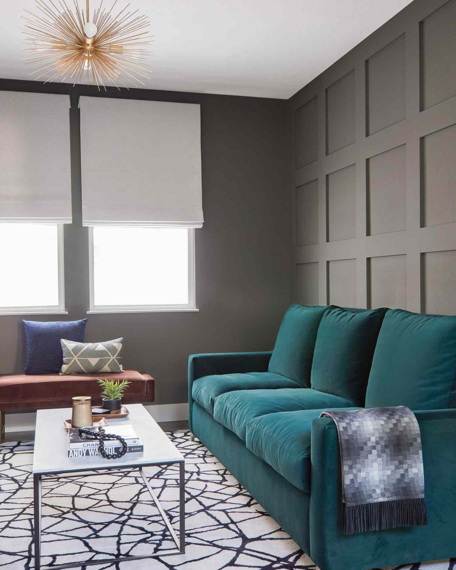 Sala cinza com sofá de veludo azul-petróleo e lustre starburst 