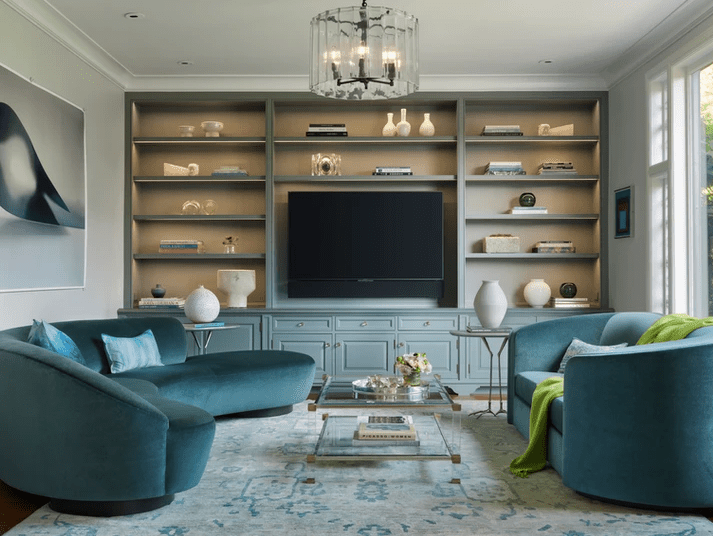 Wohnzimmer mit serpentinenförmigen tealfarbenen Sofas und hellblauen Schränken 