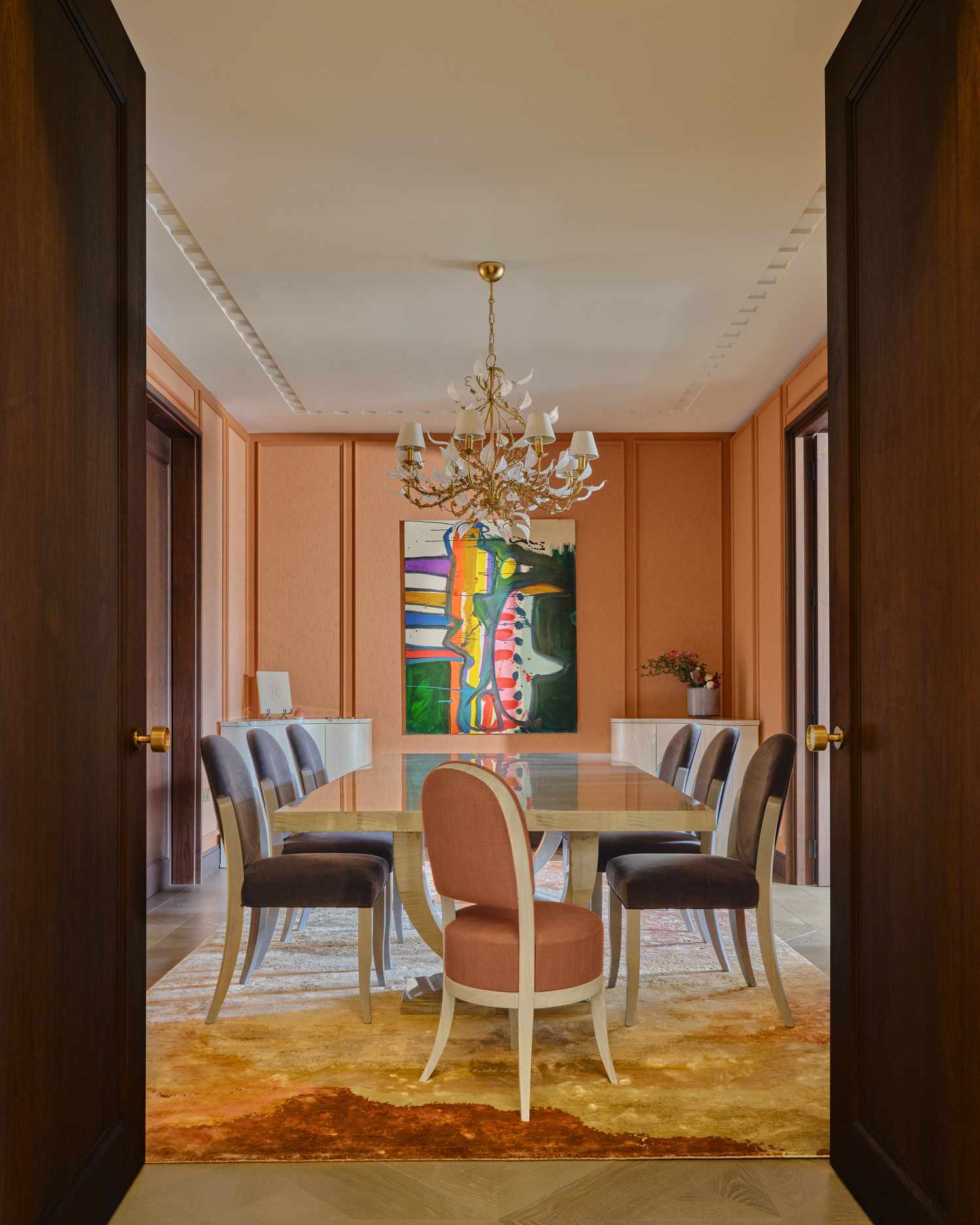 Uma sala de jantar é pintada em uma cor pêssego quente e tem uma mesa com cadeiras azuis suaves