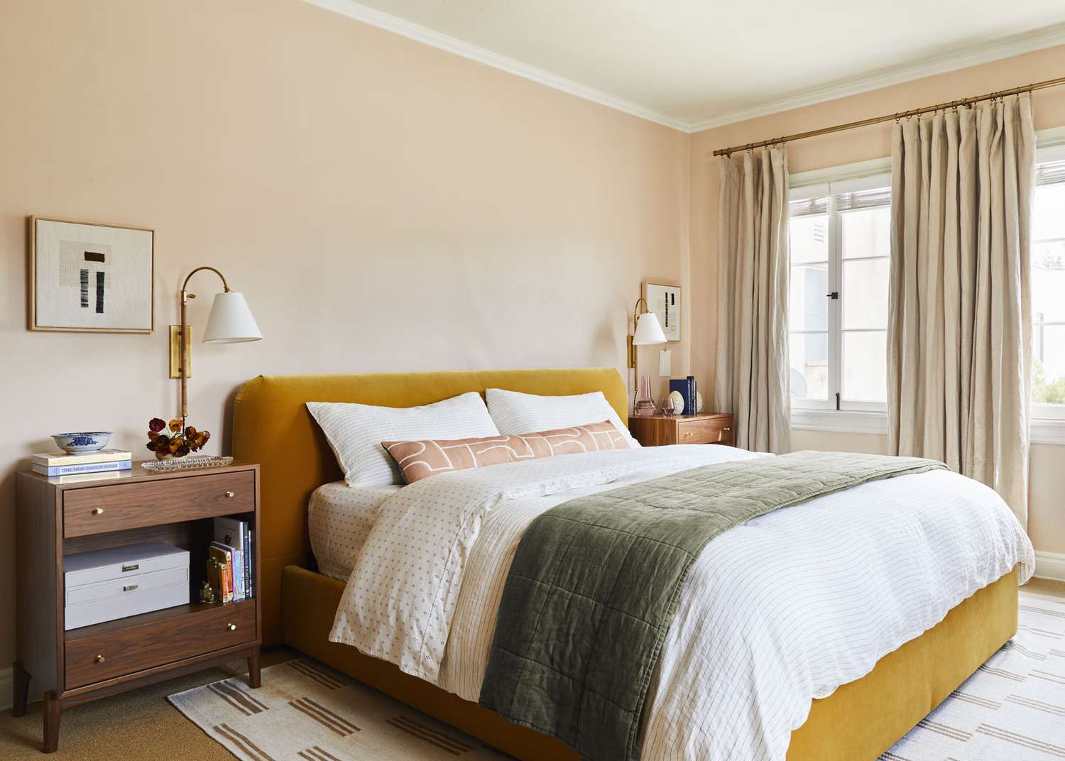 Una cama de color amarillo mostaza se apoya contra una pared de suave color melocotón