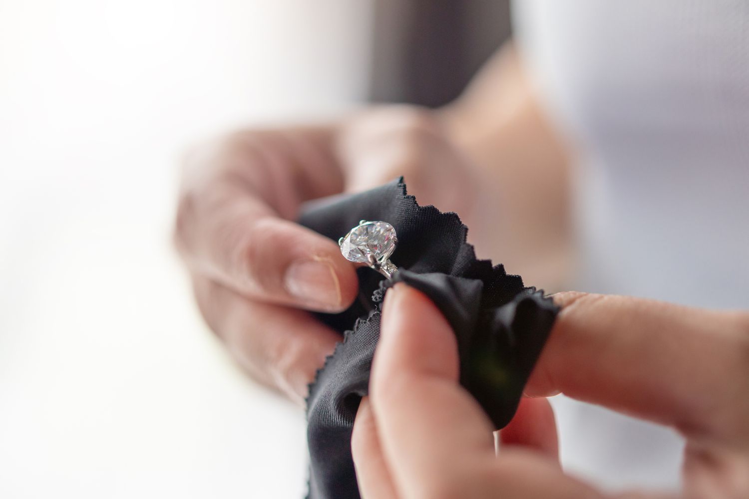 Frau reinigt Schmuck Diamantring mit Stofftuch