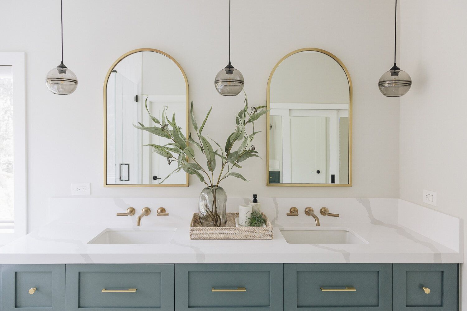Banheiro branco com armários em azul-petróleo e espelhos dourados