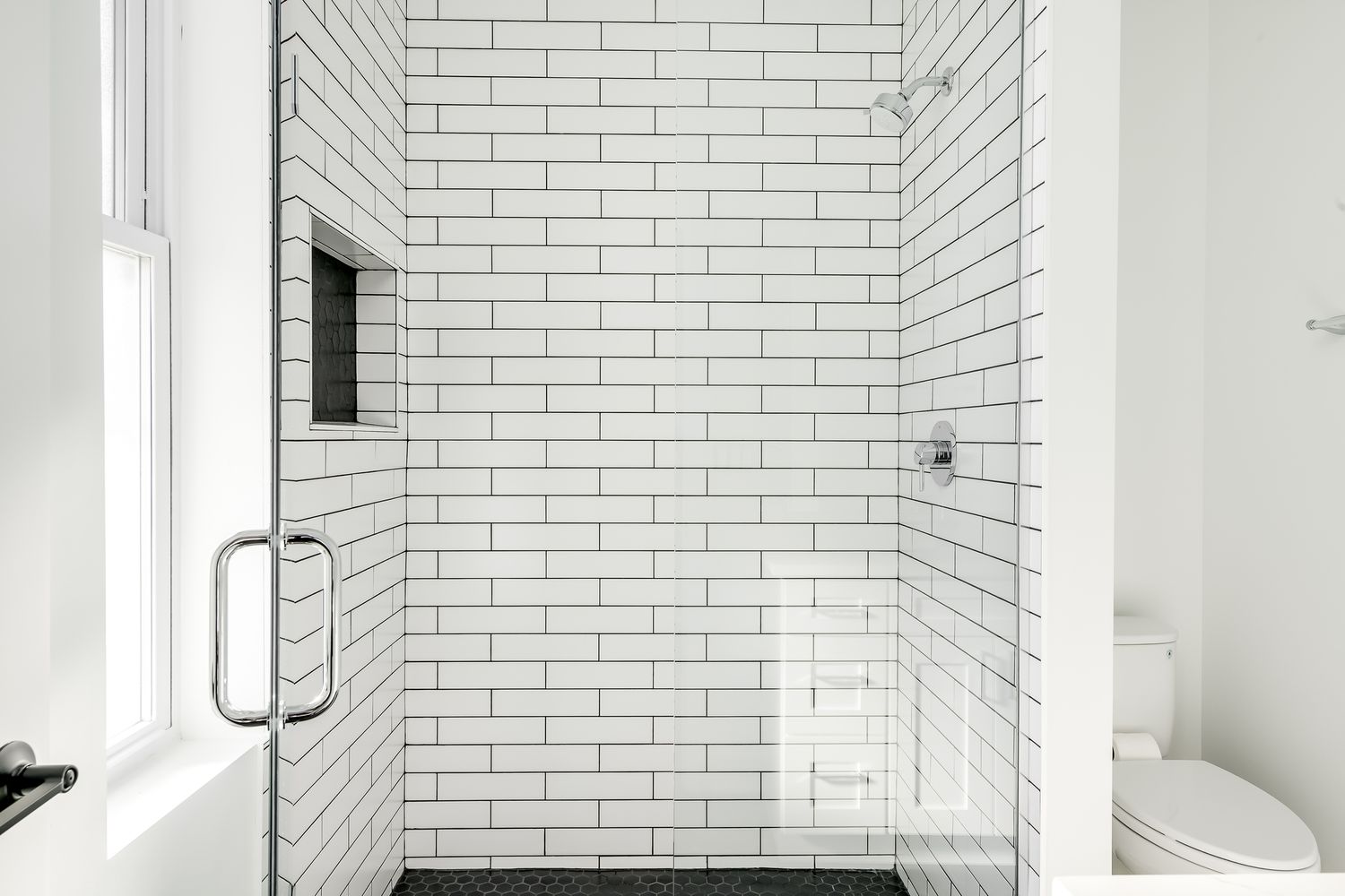 Rejunte preto com azulejo branco e nicho e piso pretos no chuveiro