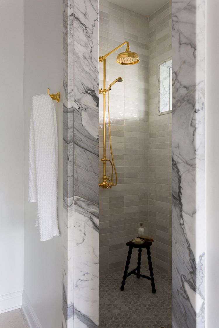 Kompakte Dusche mit Marmoreinstieg, goldenen Armaturen und Fenster