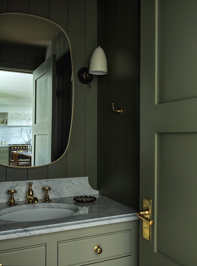 Banheiro verde com revestimento de parede, bancada de mármore, detalhes em latão