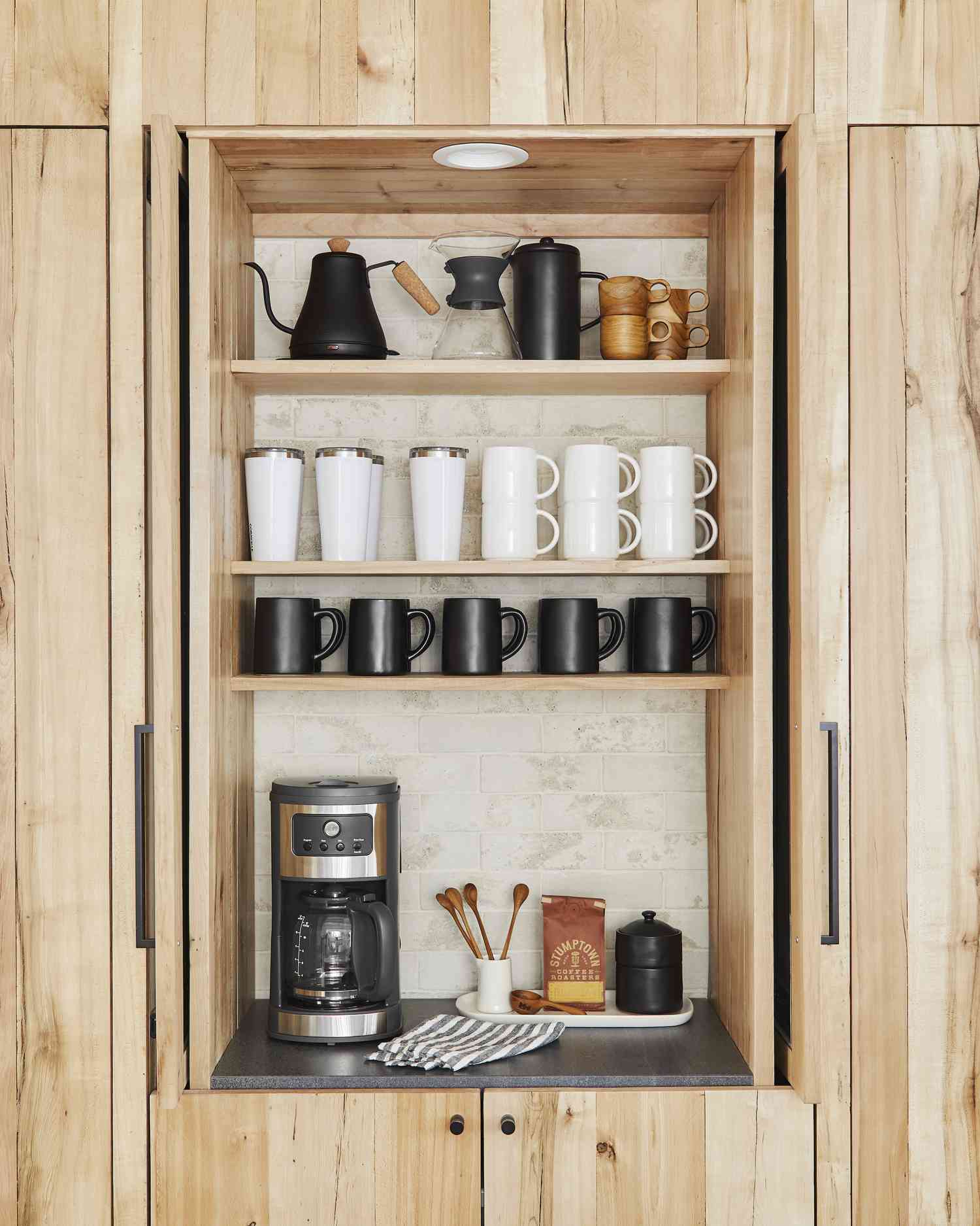 Armário de madeira com cafeteiras, canecas e acessórios em seu interior