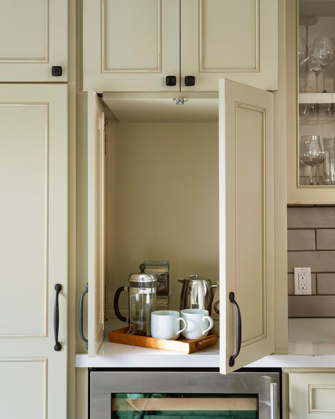 Armoire couleur crème avec presse à café et mugs à l'intérieur