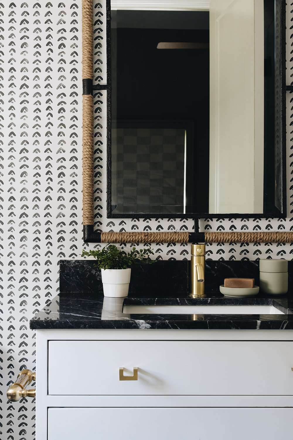 Banheiro com decoração em preto e branco, papel de parede, espelho de corda