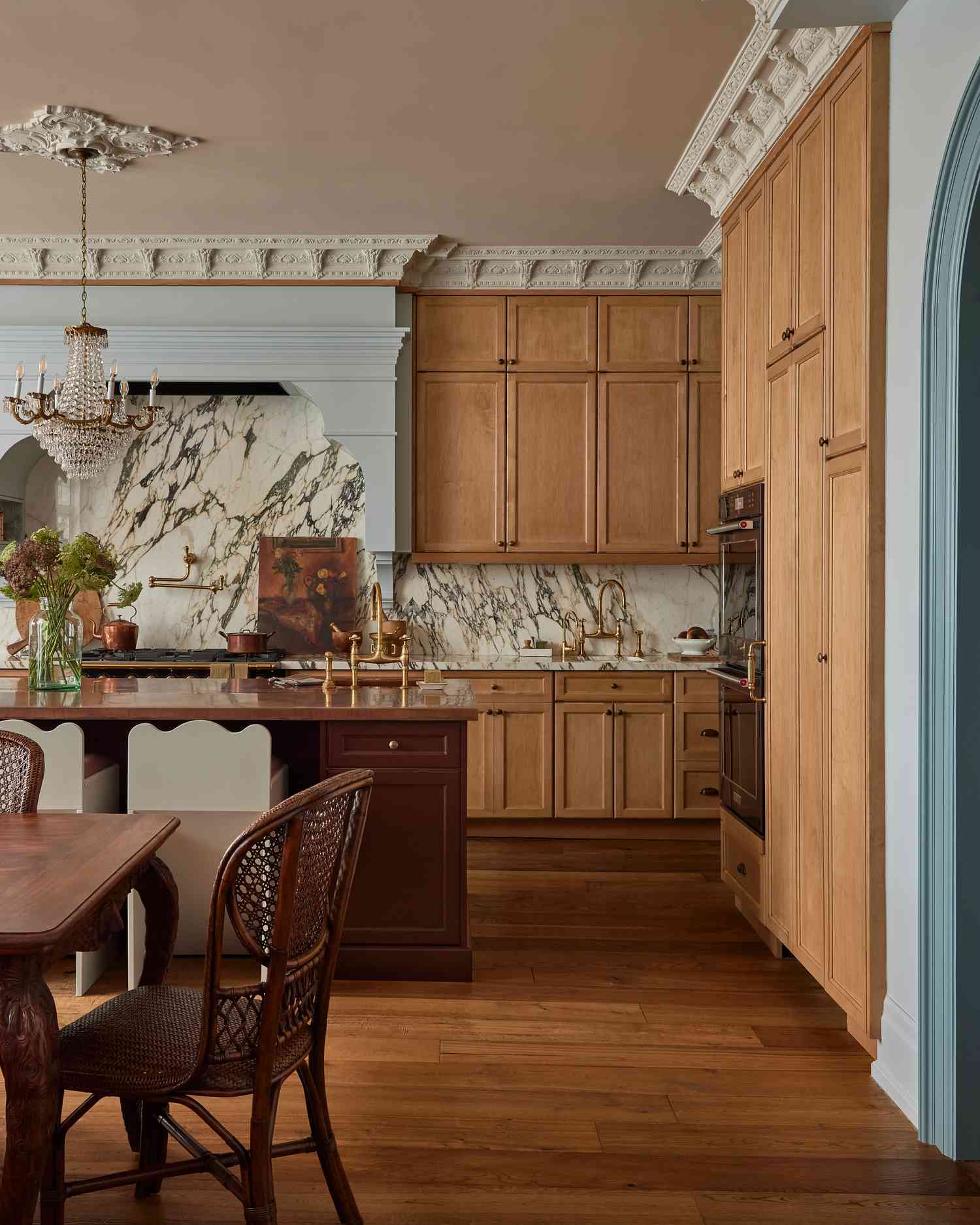 Eine maßgeschneiderte Küche mit verschnörkelten Verzierungen, einem Kronleuchter, flankiert von einem dekorativen Deckenmedaillon, und einer hellblauen Dunstabzugshaube