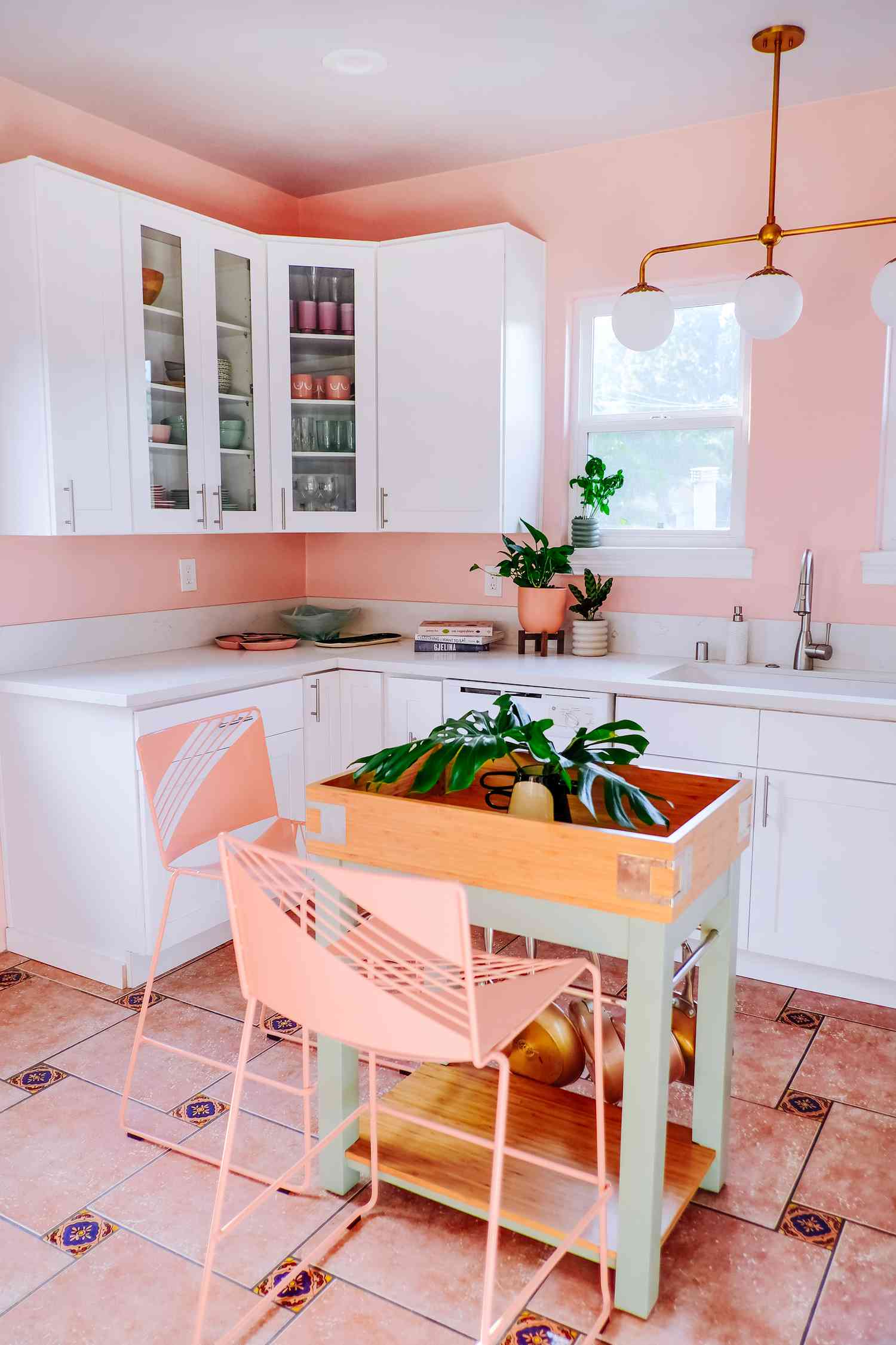 Uma cozinha rosa e branca com uma pequena ilha