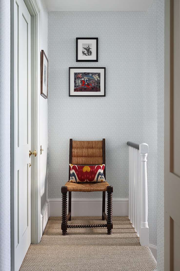Uma cadeira no final de um corredor estreito com obras de arte acima dela