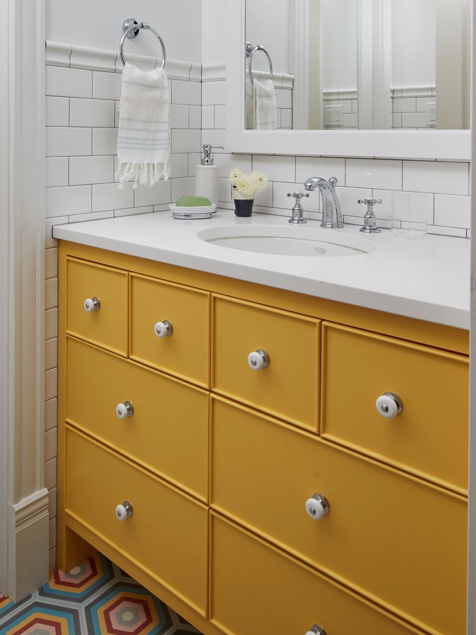Cuarto de baño con armarios amarillos y suelo de baldosas de colores 