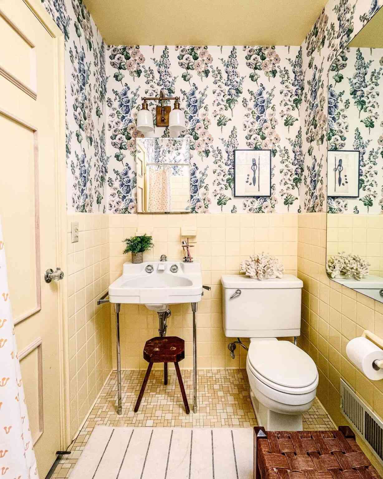 Baño amarillo pálido con papel pintado floral y azulejos vintage 