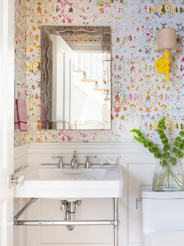 Baño blanco con papel pintado amarillo y rosa y aplique amarillo 