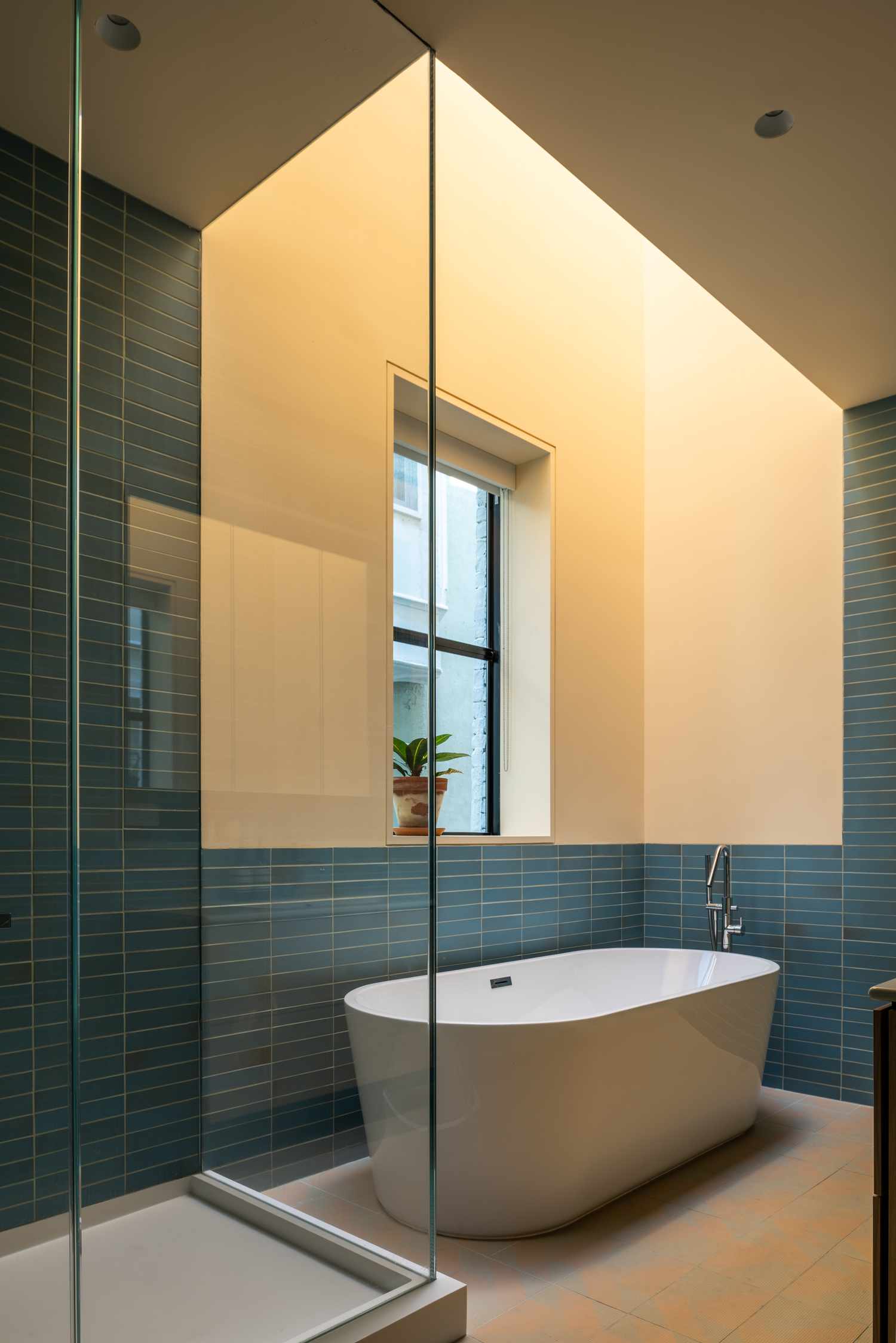 Gelbes Badezimmer mit hellgelben Wänden, freistehender Wanne und modernen blauen Fliesen