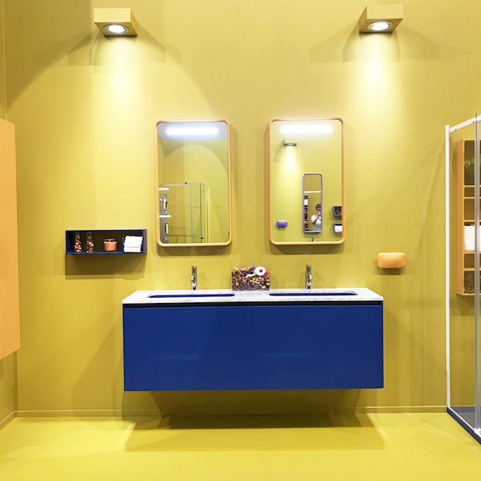 gelbes Badezimmer mit blauem Waschbecken und blauem Schwebeboxregal