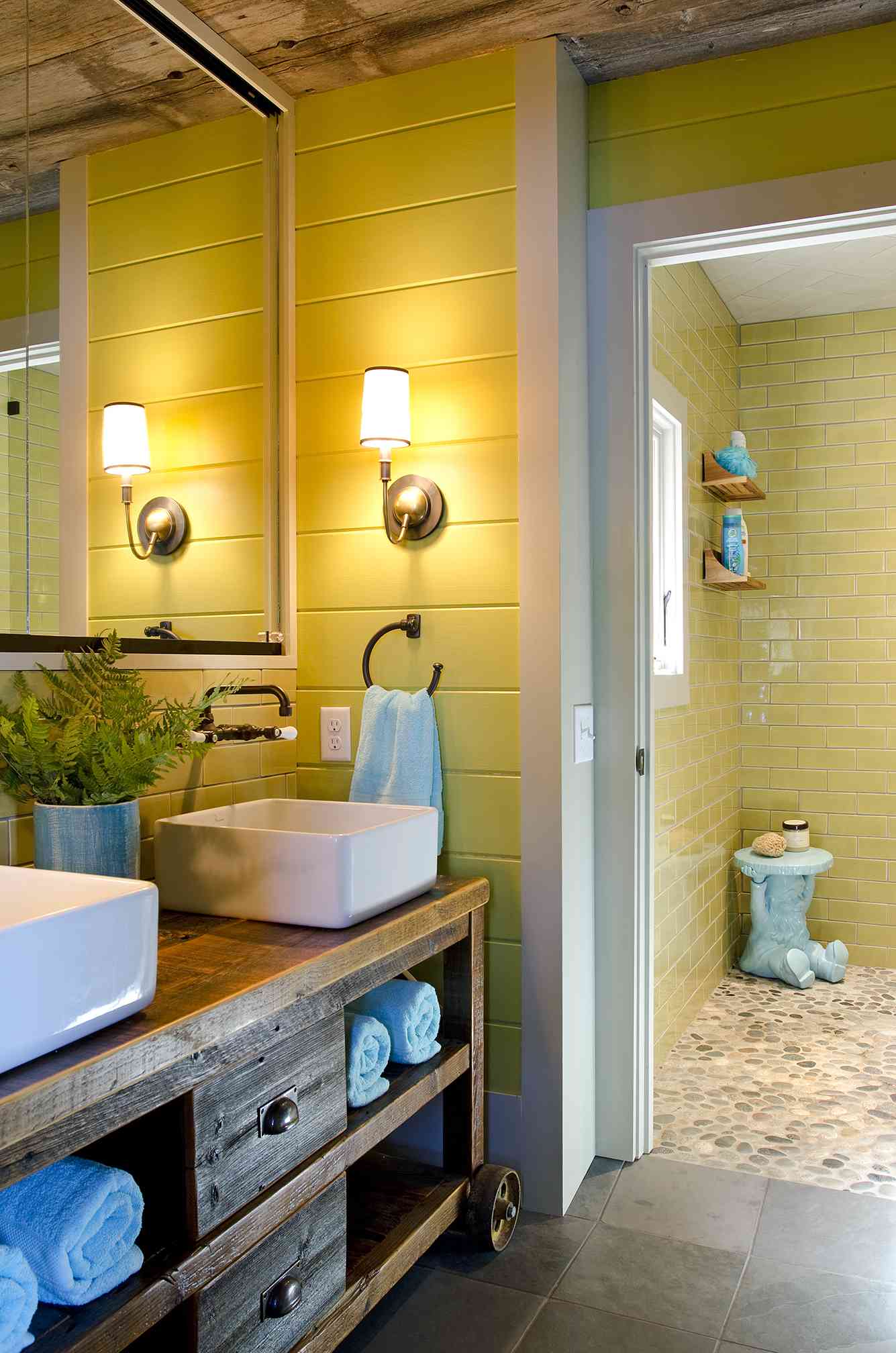 Rustikales gelbes Badezimmer mit Lattenzaun, Eitelkeiten aus Holz und gelber Unterflur-Dusche