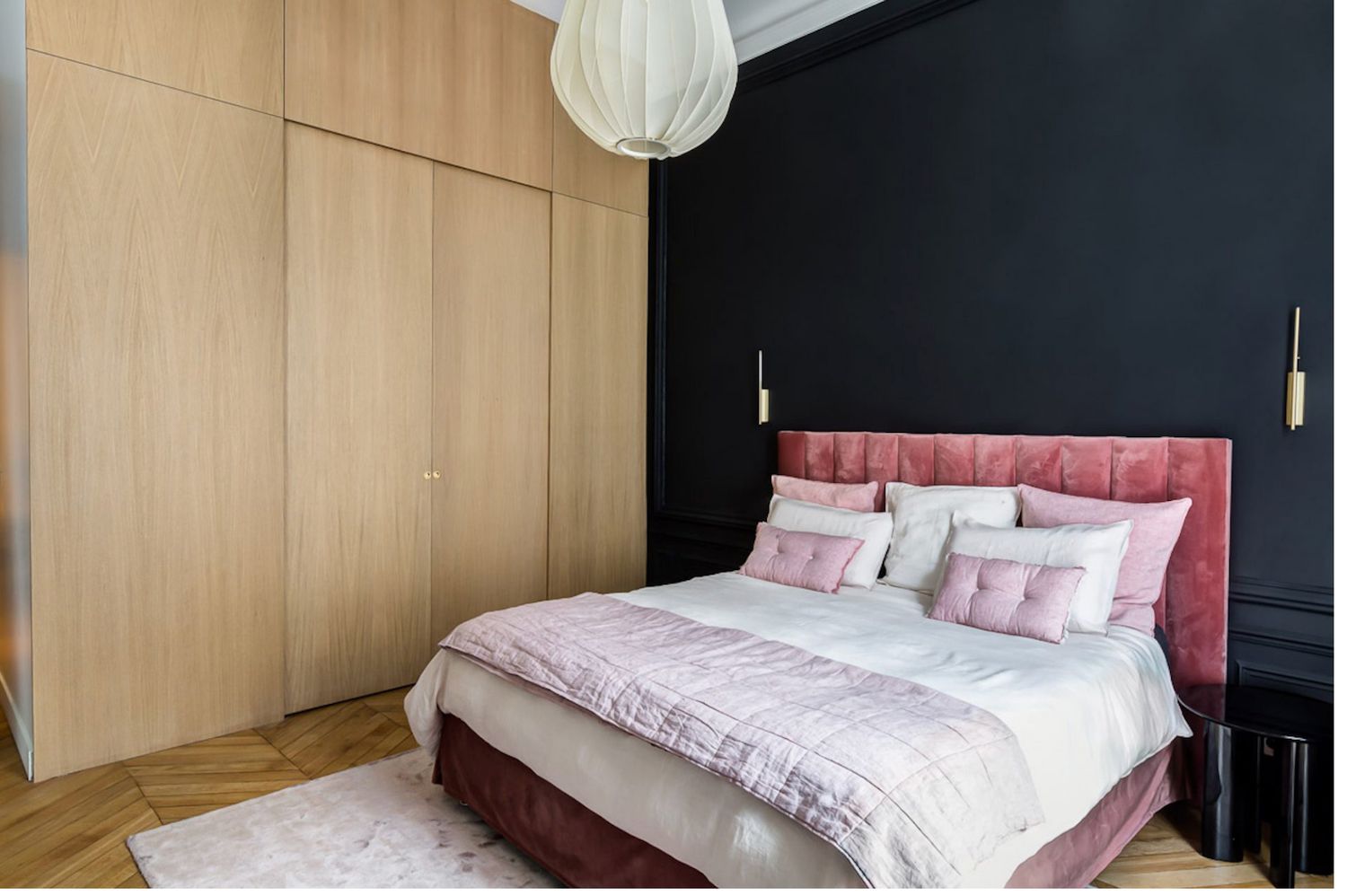 parede de acento preta com cabeceira rosa no quarto