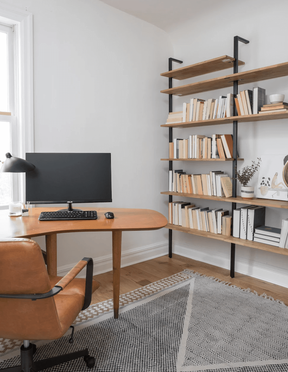 Un bureau à domicile avec un bureau géométrique, une chaise de bureau à roulettes, et beaucoup d'espace pour se déplacer