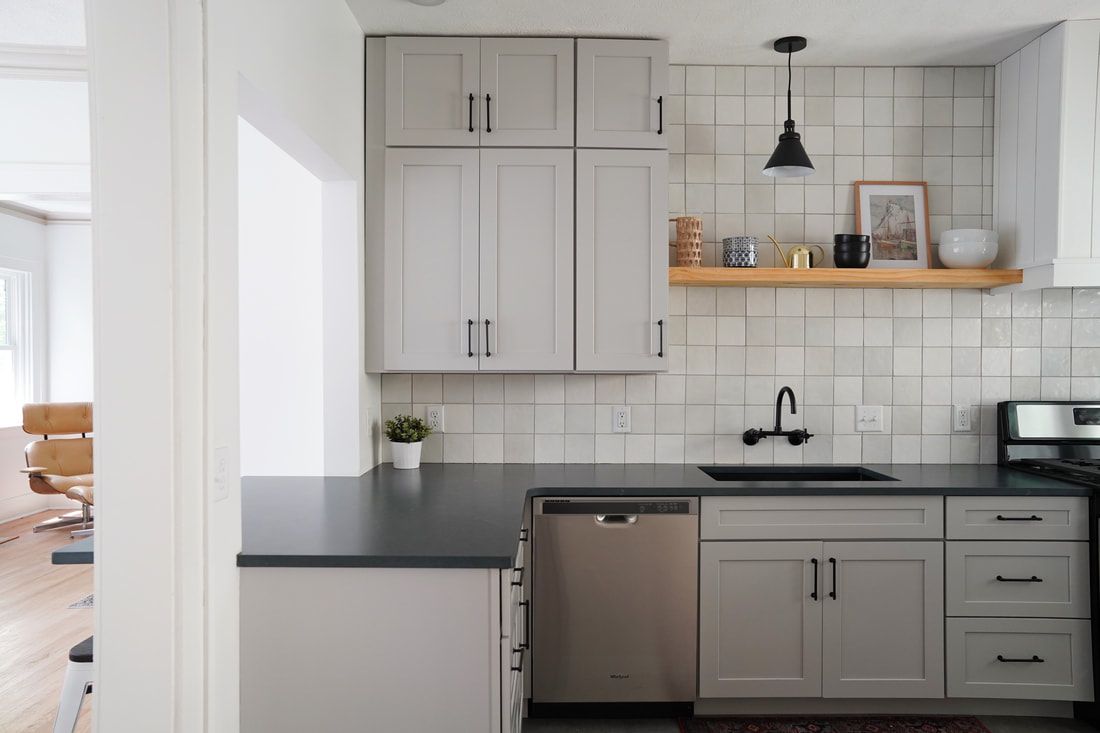 Uma cozinha com armários cinza suave e bancada de granito preto