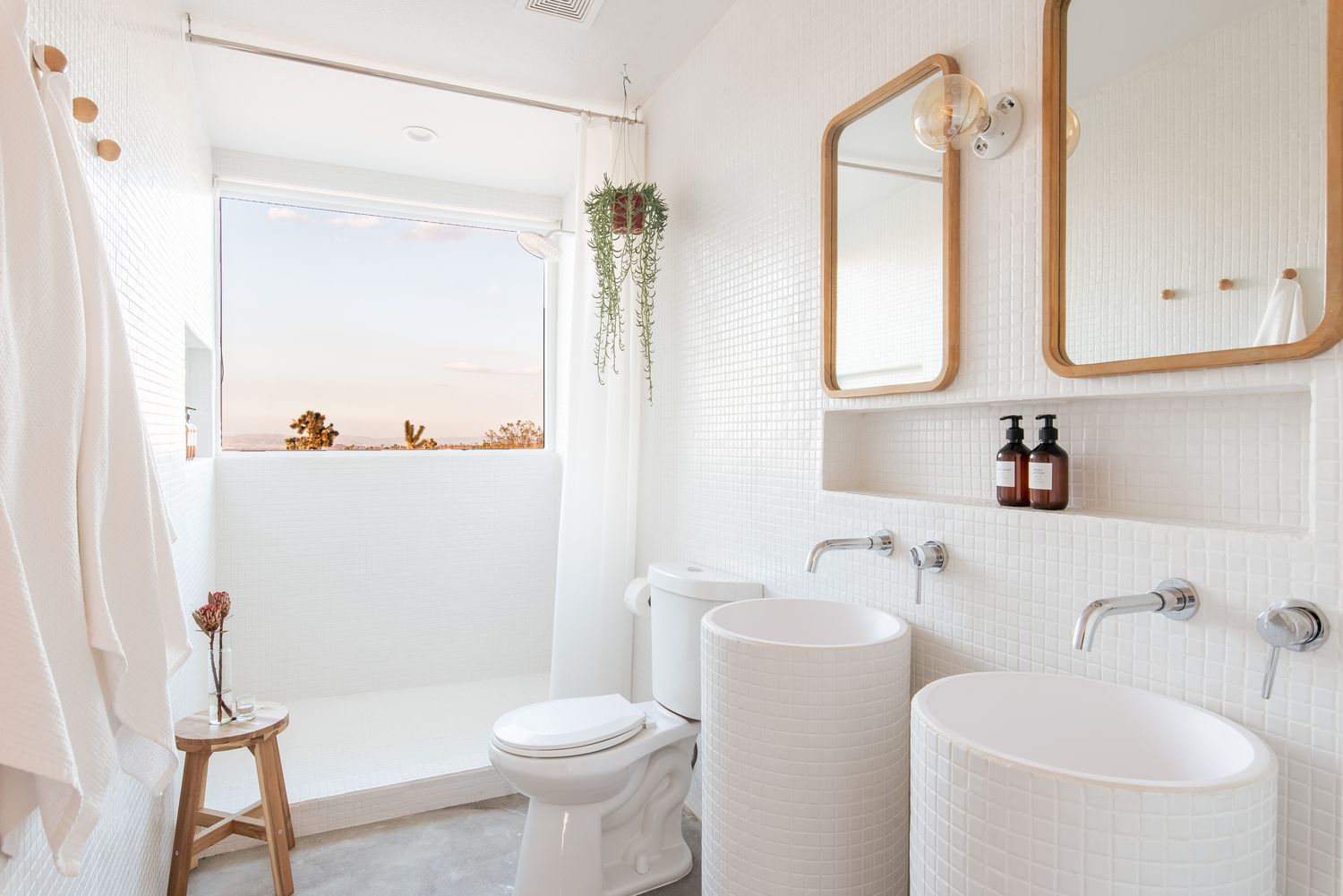 Banheiro pequeno remodelado todo branco com planta suspensa, azulejo de mosaico branco e janela do chuveiro