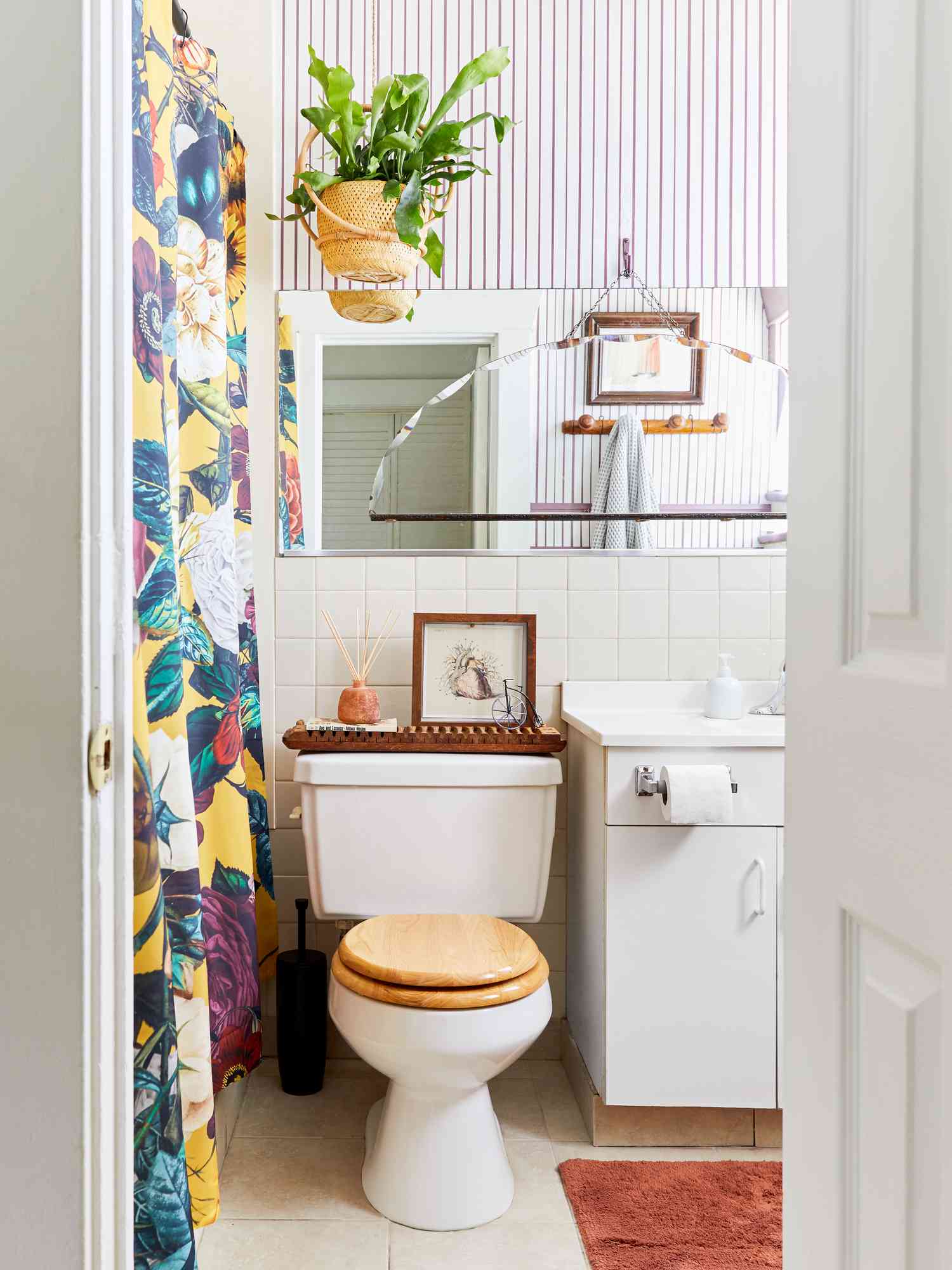 Un cuarto de baño blanco liso con características de madera consigue un estallido de patrones con una cortina de ducha audazmente modelada