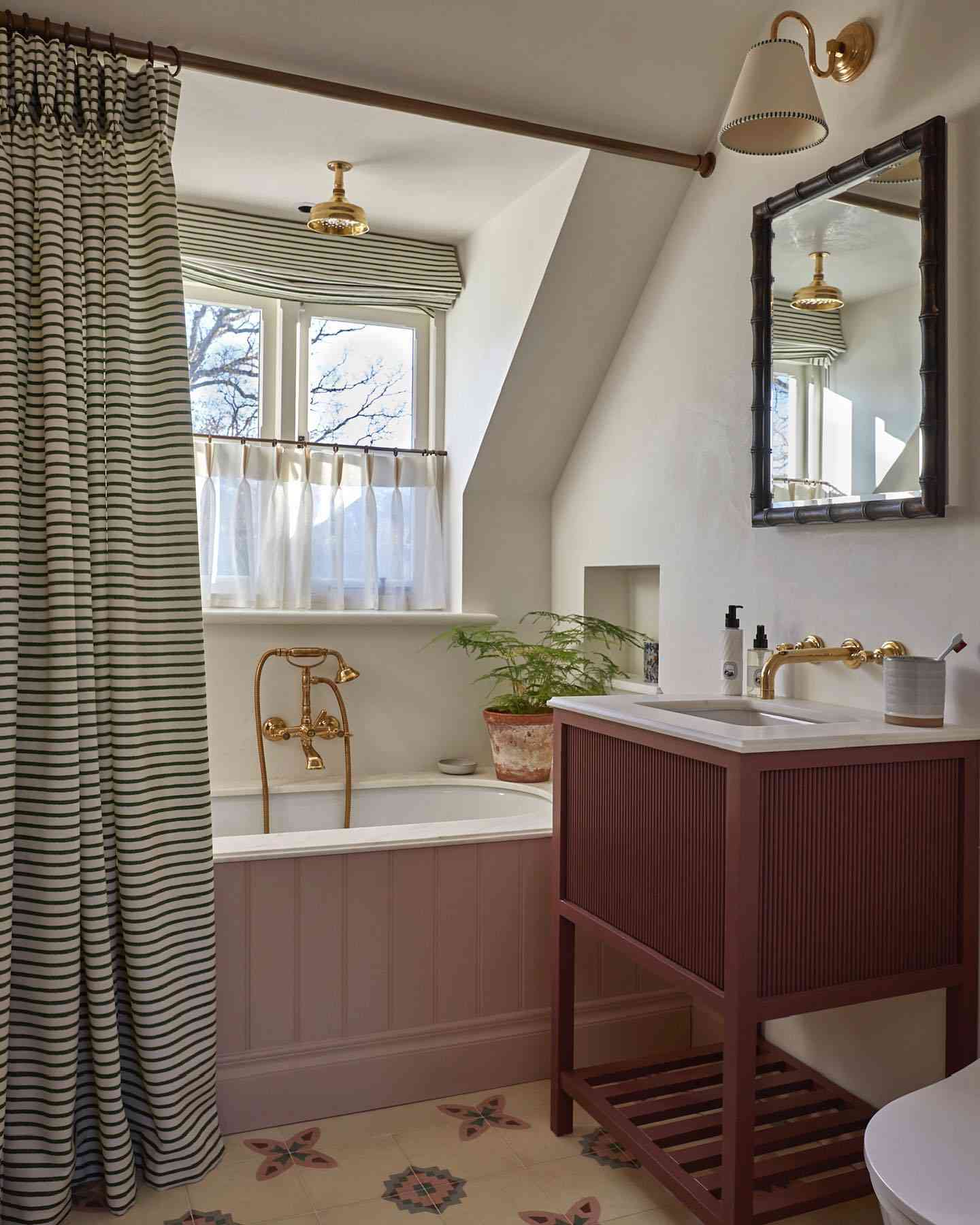 Baño con detalles dorados y cortina de ducha a rayas