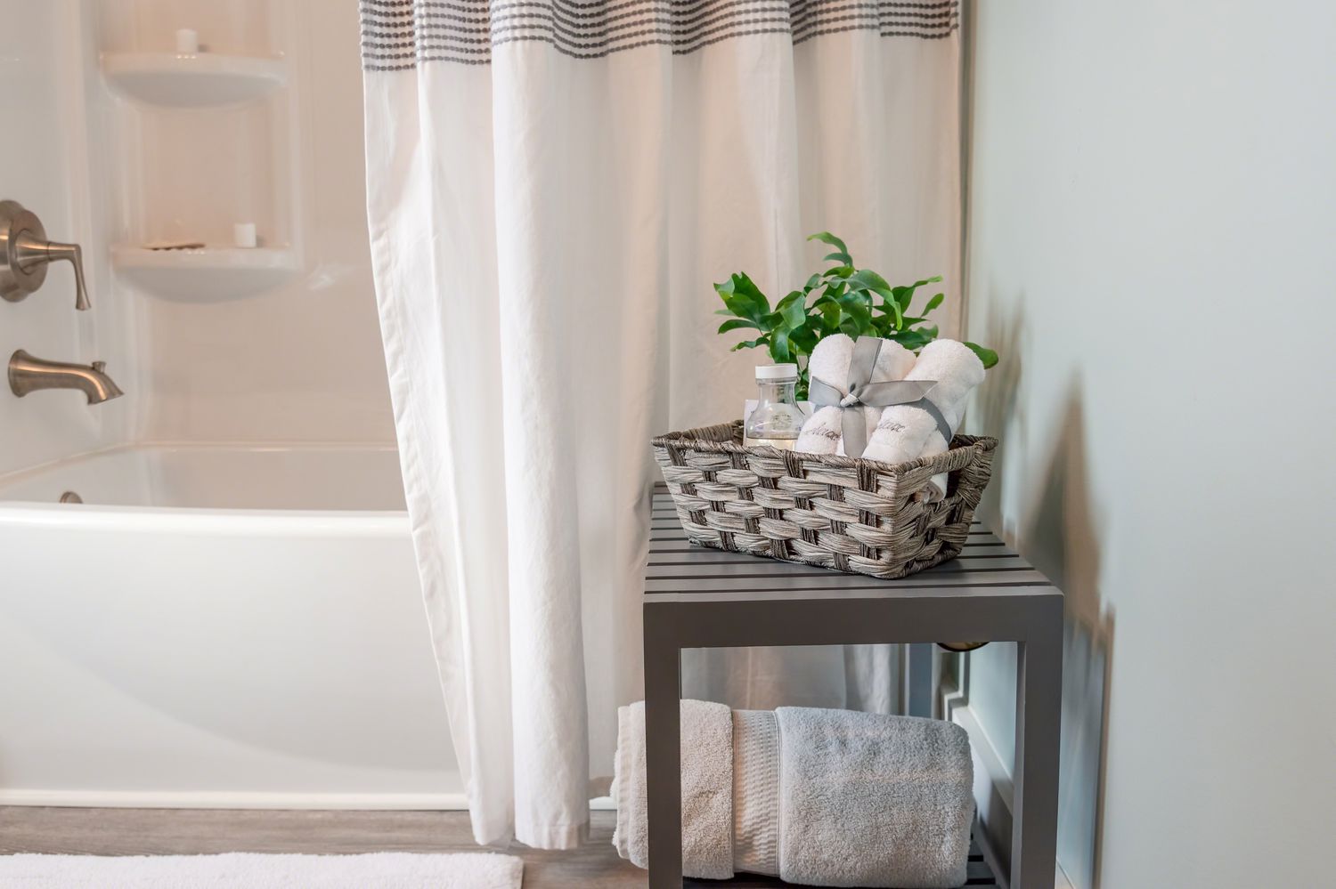 Un rideau de douche gris et blanc assorti à la minuscule table d'articles de toilette 