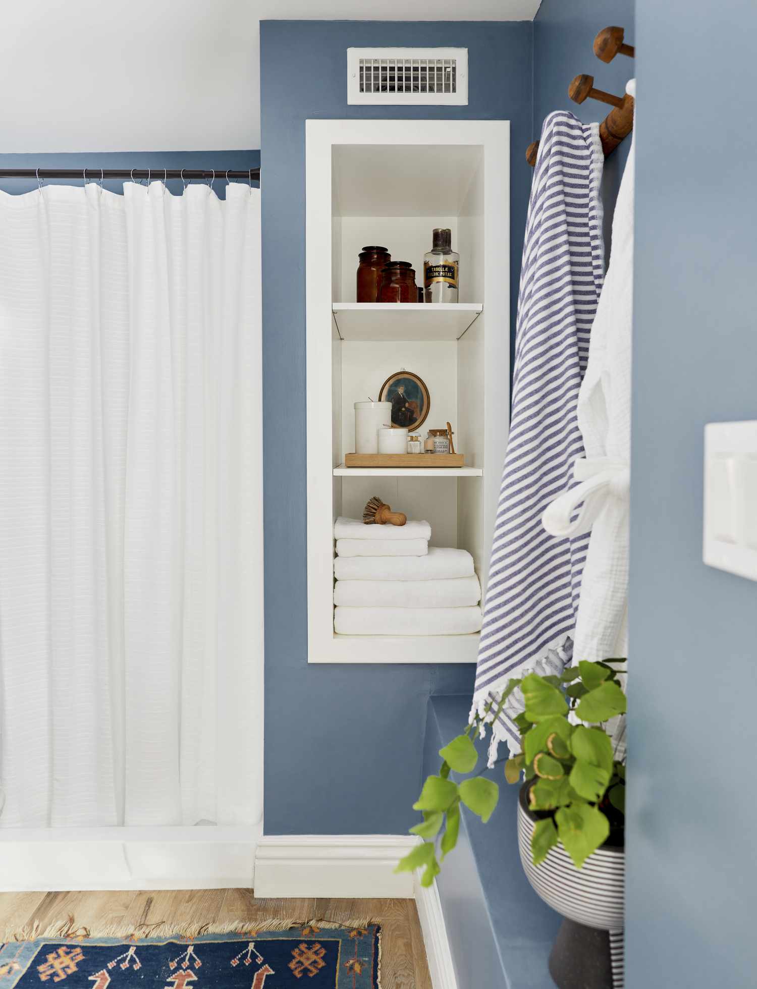 Une salle de bain peinte dans un ton bleu doux a un rideau de douche blanc
