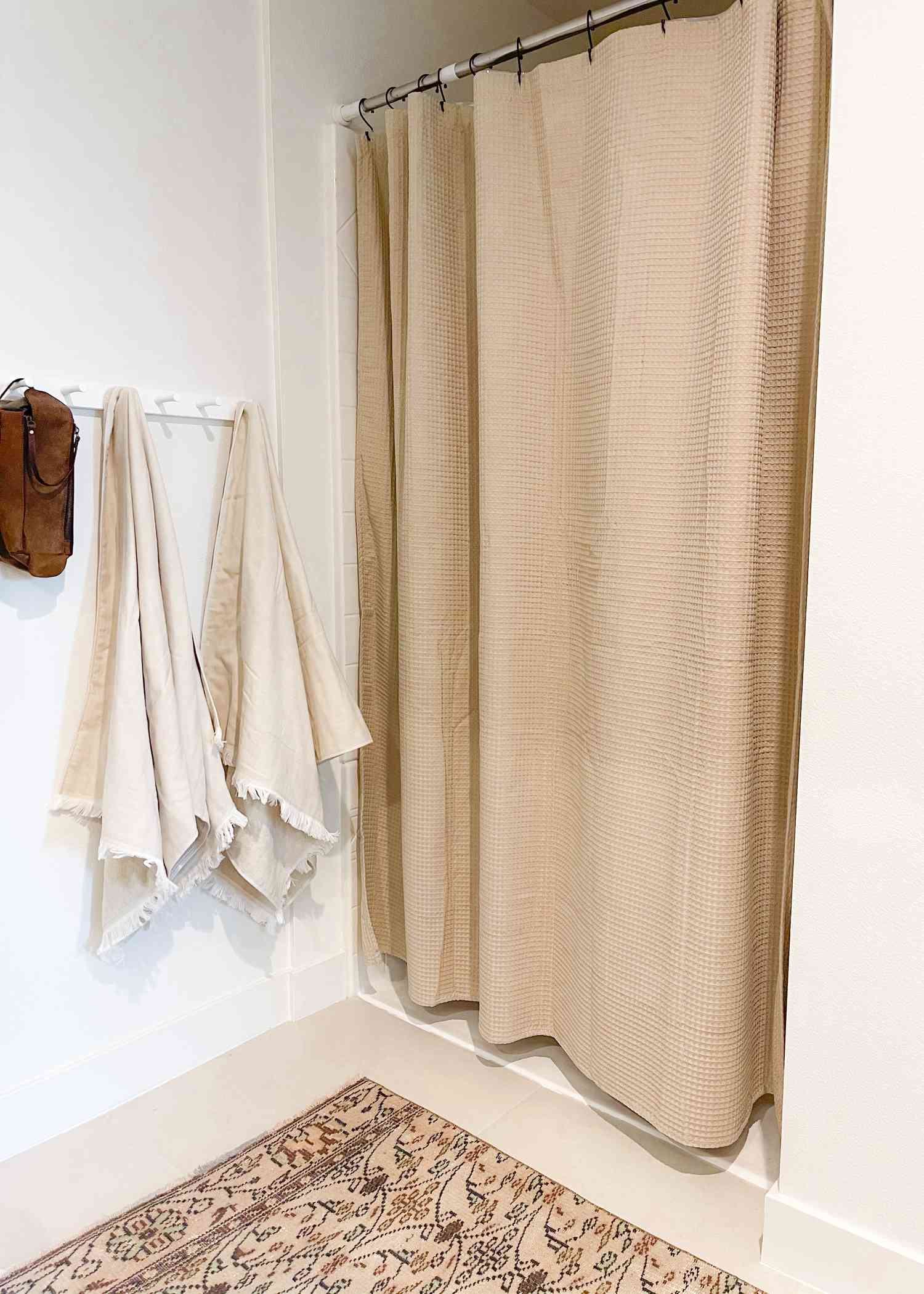Uma cortina de chuveiro bege é usada em um banheiro branco