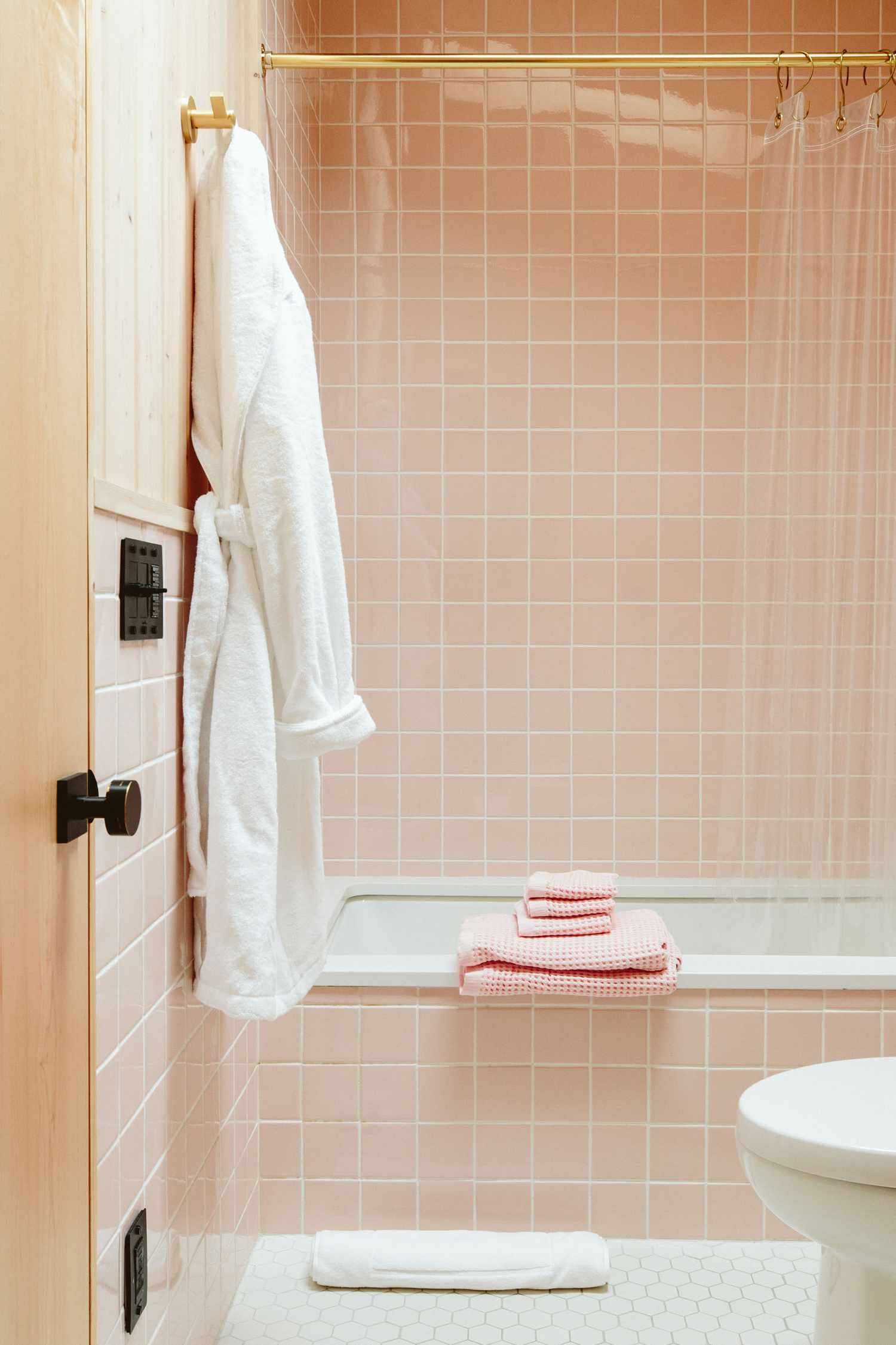 Une salle de bain rose pâle est autorisée à briller avec un rideau clair montrant le carrelage rose