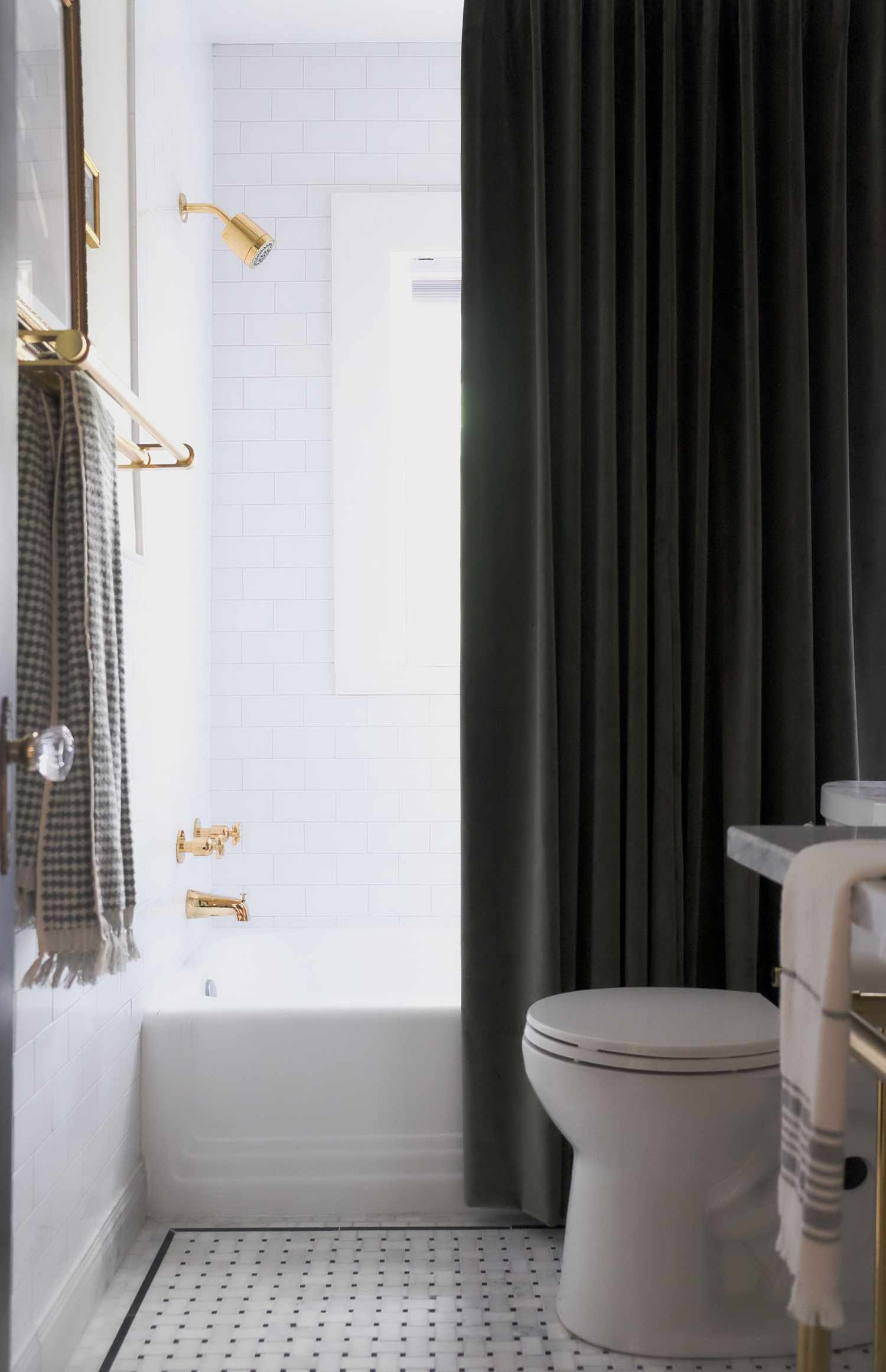 A tall dark shower curtain stands out in a mostly white bathroom