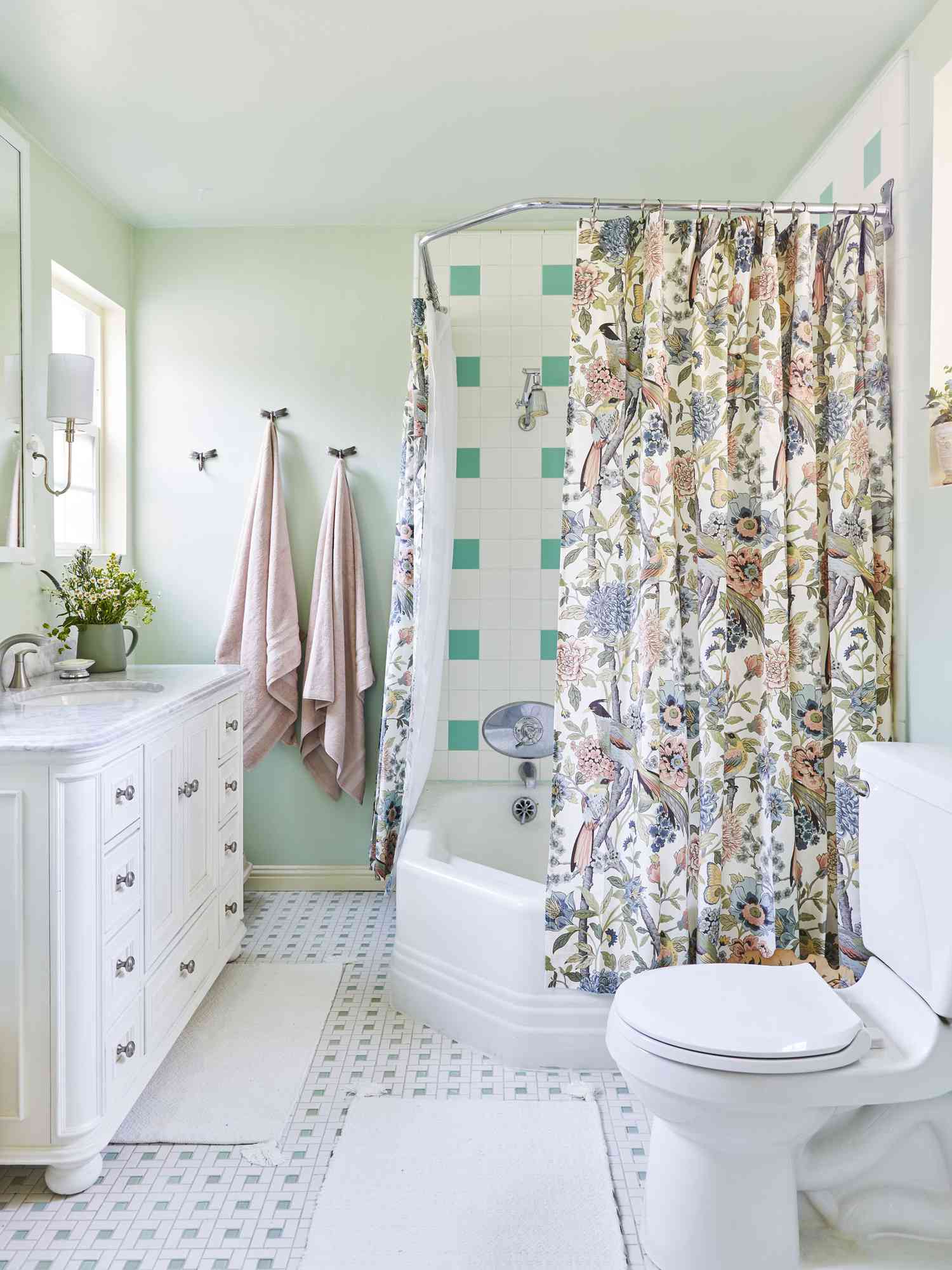 Colorful shower curtain in floral patterns is pared with walls painted in muted green tones